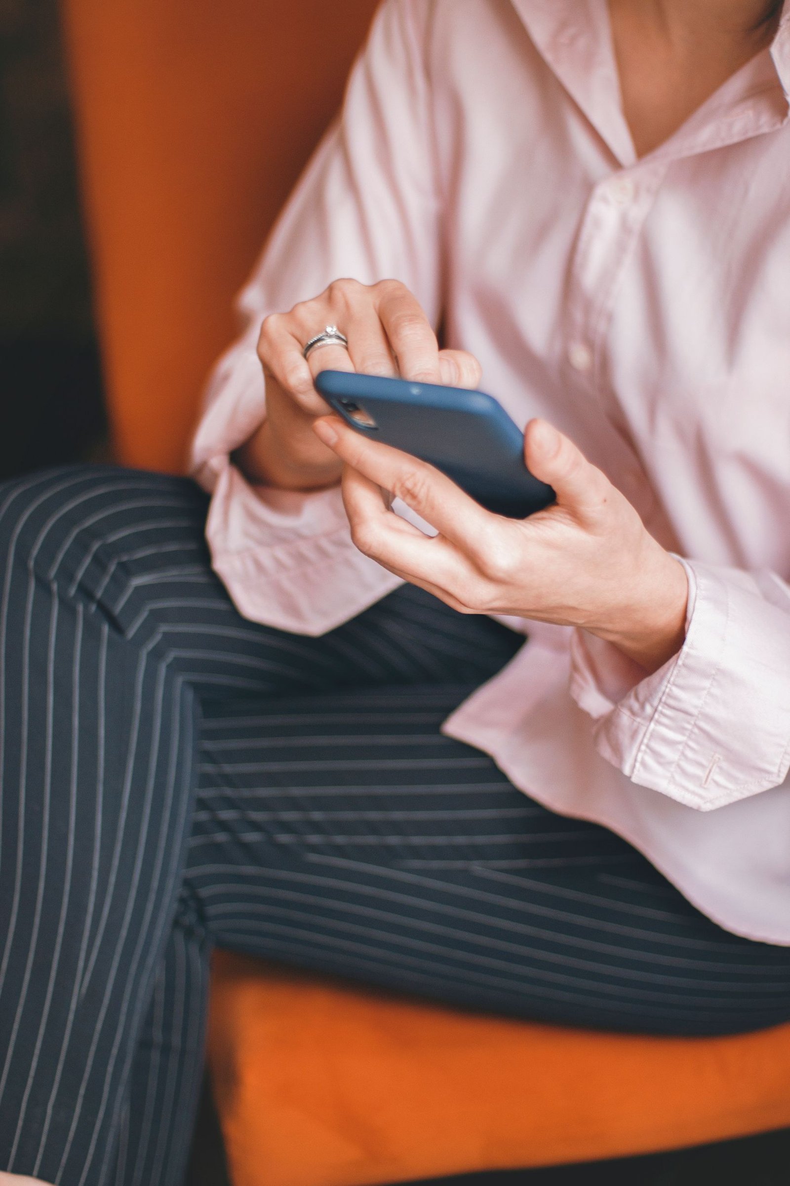 Adult woman using a smartphone while sitting, conveying relaxation and technology use.