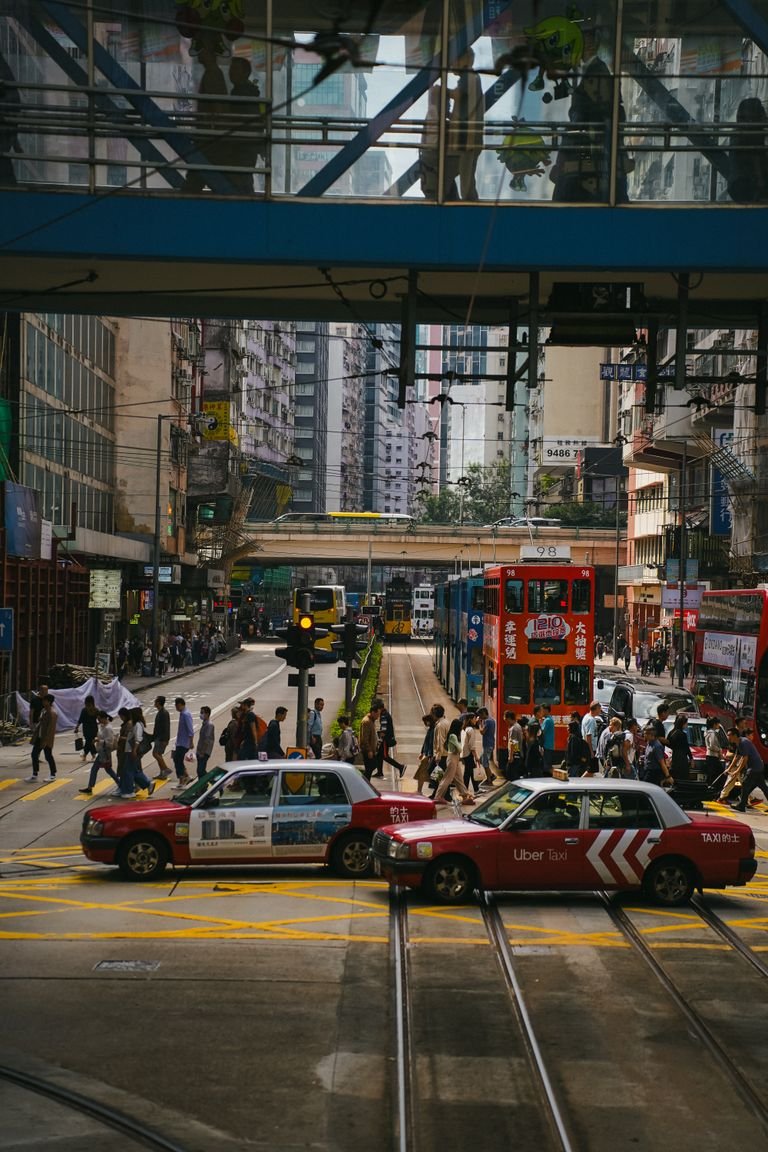 Dynamic urban scene in Hong Kong featuring busy streets, trams, and vibrant pedestrian activity.